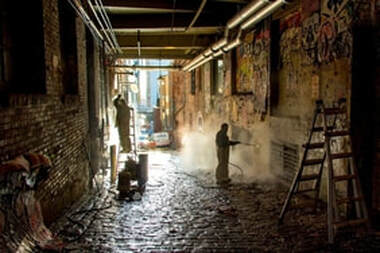 Concrete contractors get to work cleaning the inside of an alleyway